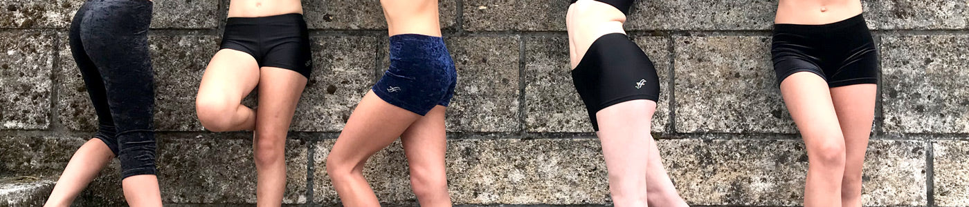 Verschiedene Turnhosen für Mädchen mit Shorts, Leggings und Samtshortys vor Steinwand